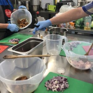 Photograph of people preparing food in a large kitchen